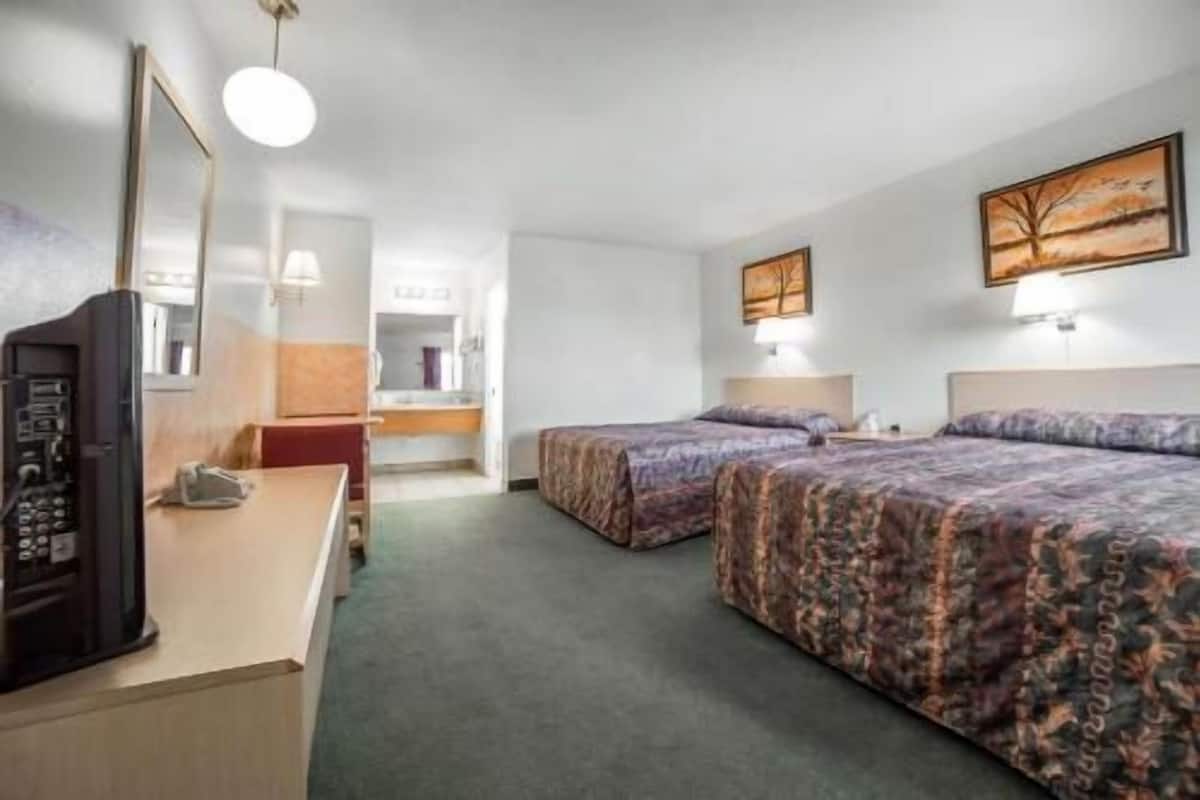 A hotel room with two beds, a desk with a telephone, and a television.
