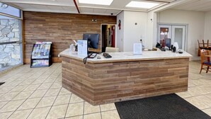 A reception desk with a wooden finish, a computer, and a phone. There are informational brochures on the left. - Rodeway Inn Boardman - Hermiston (Boardman)