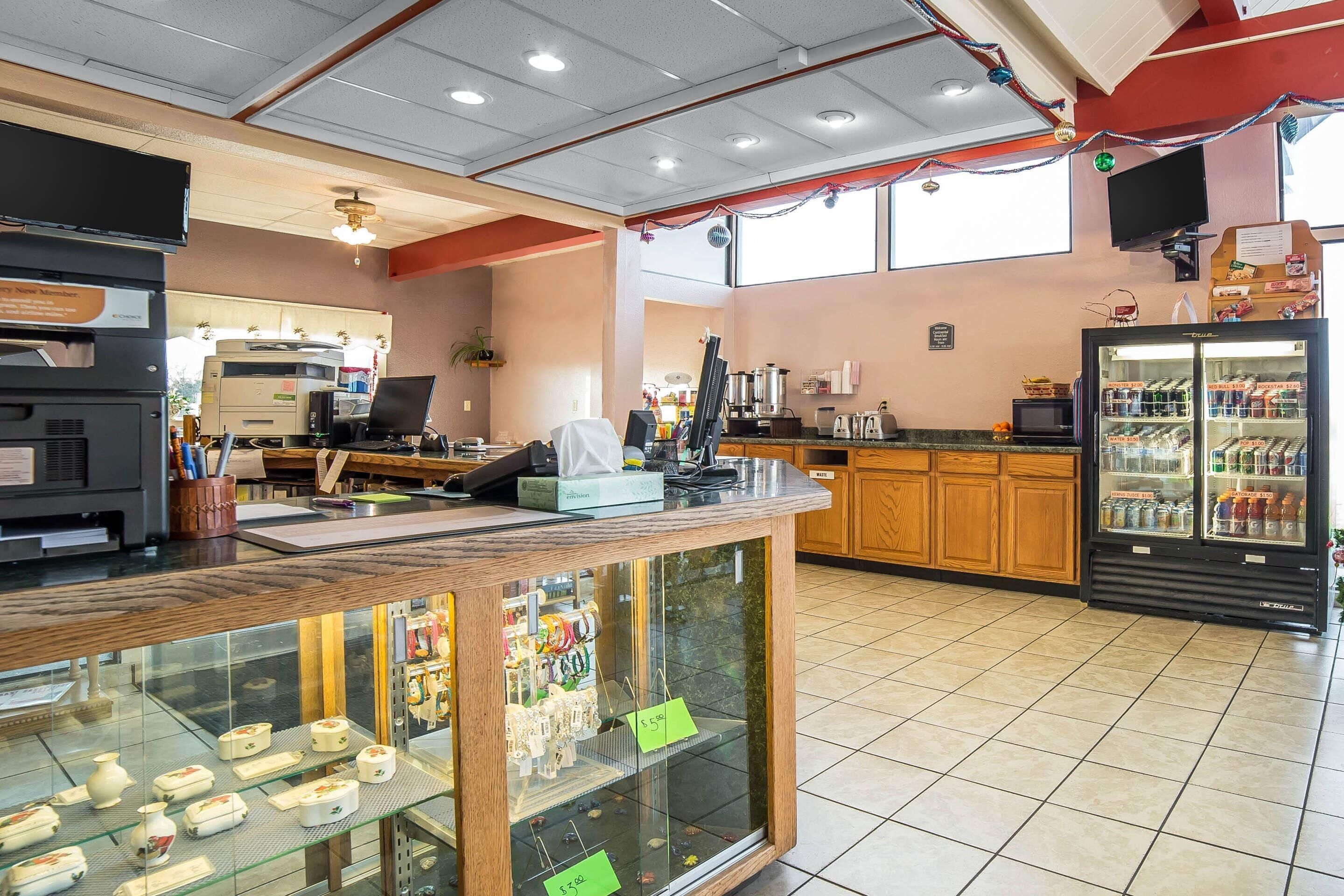 Interior de un restaurante con mostrador, vitrina, zona de cocina y refrigerador.