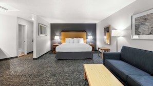 Een hotelkamer met een groot bed, een bank, een bijzettafeltje en twee bedlampjes.