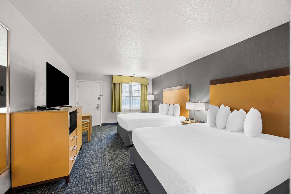 A hotel room with two beds, a TV, a desk, and a wardrobe.