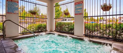 Un jacuzzi con barandilla metálica, rodeado por una cerca y un cartel con las normas del spa.