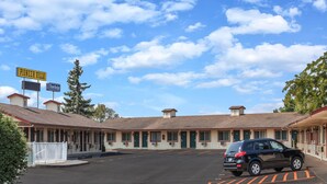 A motel with a parking lot and a car parked in front. - Travelodge by Wyndham Pioneer Villa (Halsey)