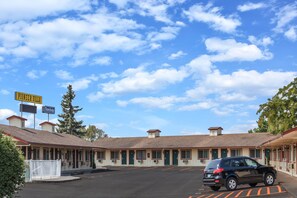 Un motel con estacionamiento y un coche aparcado delante.