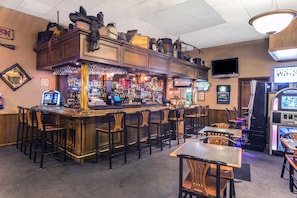 A bar with multiple stools and a counter, equipped with a cash register and various bottles. - Travelodge by Wyndham Pioneer Villa (Halsey)