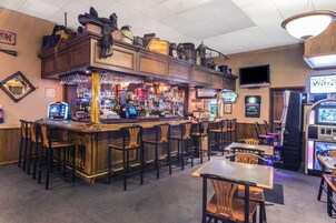 Um balcão de bar com vários bancos, equipado com uma máquina registadora e diversas garrafas.
