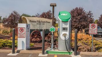 Una estación de carga para vehículos eléctricos con un cartel que dice 'Pioneer Villa Truck Plaza Halsey, Ore' y un letrero de 'prohibido estacionar' excepto para vehículos eléctricos en carga.
