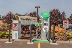 Una estación de carga para vehículos eléctricos con un cartel que dice 'Pioneer Villa Truck Plaza Halsey, Ore' y un letrero de 'prohibido estacionar' excepto para vehículos eléctricos en carga.