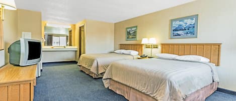 A hotel room with two beds, a desk with a television, and a bathroom.