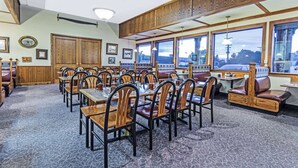 A restaurant with wooden booths and tables, framed pictures on the walls, and large windows offering a view.
