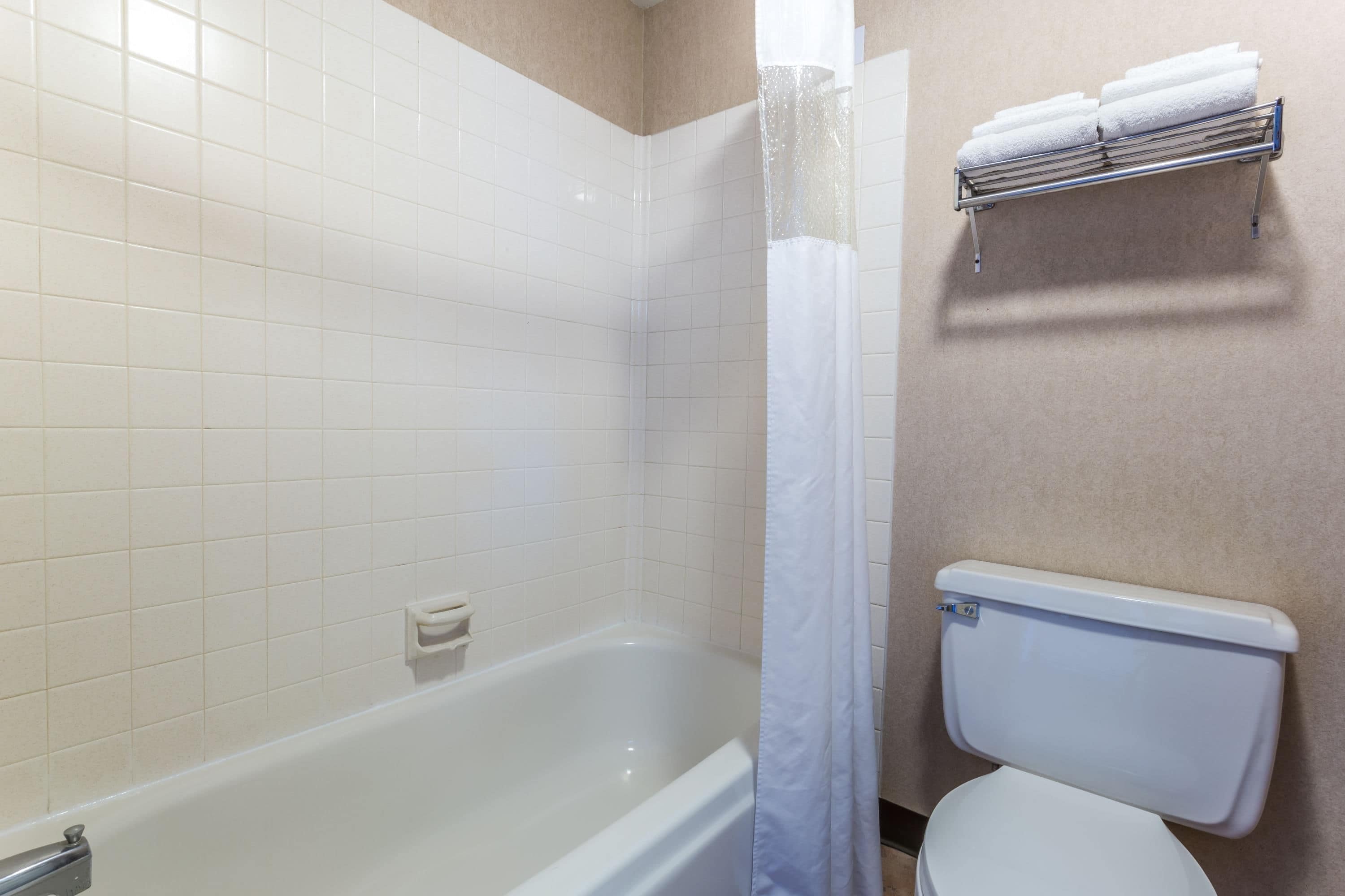 Un baño con bañera, inodoro y toallero.