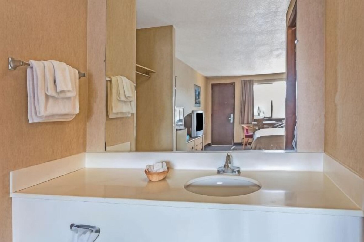 A bathroom with a sink, mirror, and towels.