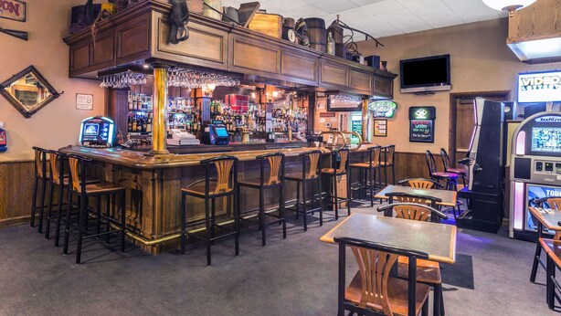 A bar area with a counter, stools, and arcade machines.
