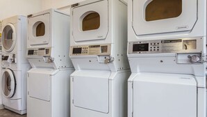 A row of white commercial washers and dryers in a facility.