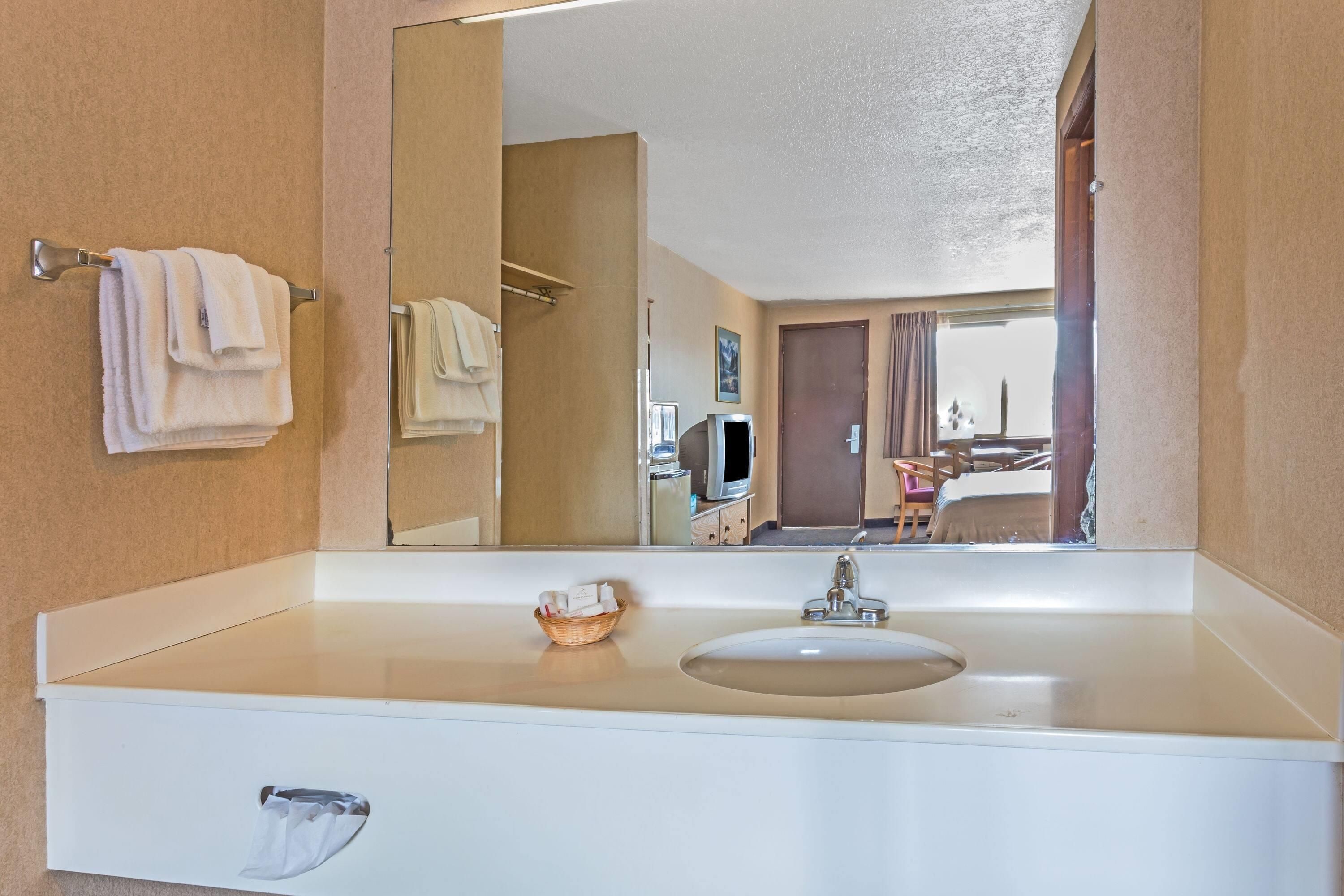 Un baño de hotel con un espejo grande, un lavabo y un perchero para toallas.