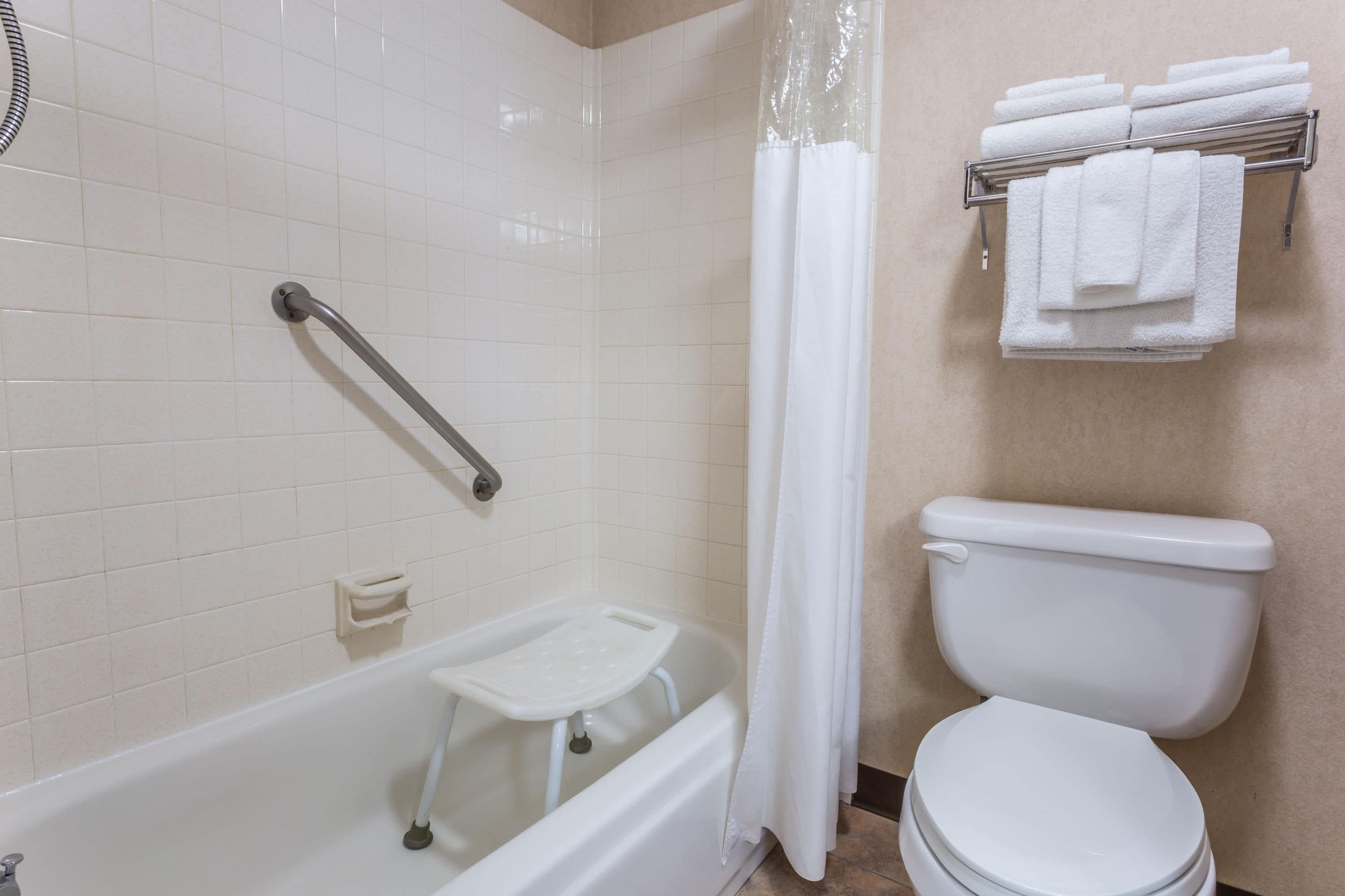 Un baño con bañera, inodoro y barra para toallas.