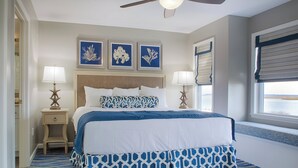 A bedroom with a bed, two bedside tables, a ceiling fan, and three framed wall art pieces. - Club Wyndham Ocean Ridge (Edisto Island)