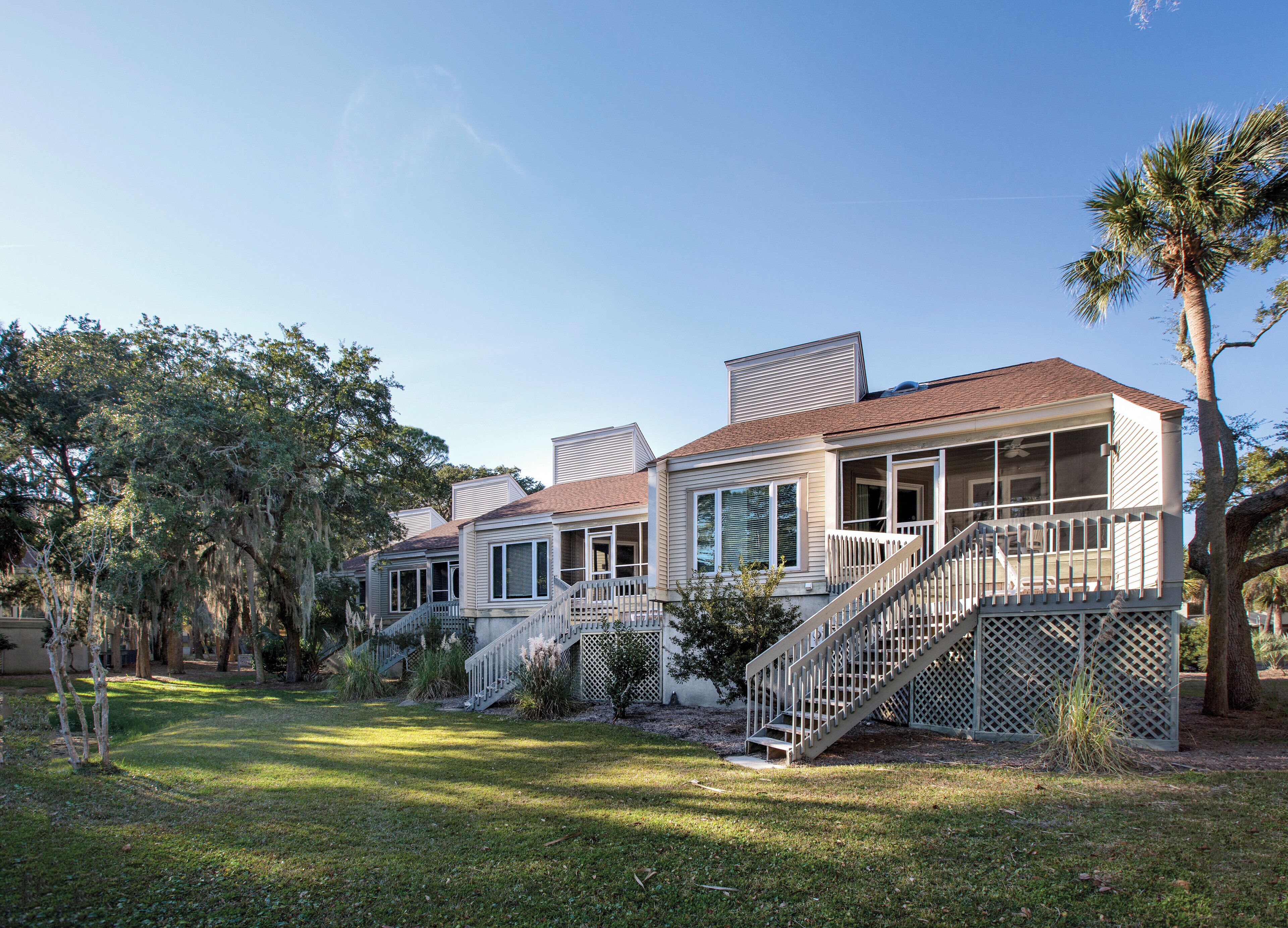 A two-story house with a porch, a staircase, and a lawn.
