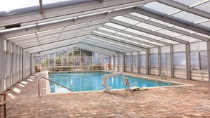 An indoor swimming pool with a glass ceiling, a brick floor, and a lifeguard chair. - Club Wyndham Ocean Ridge (Edisto Island)
