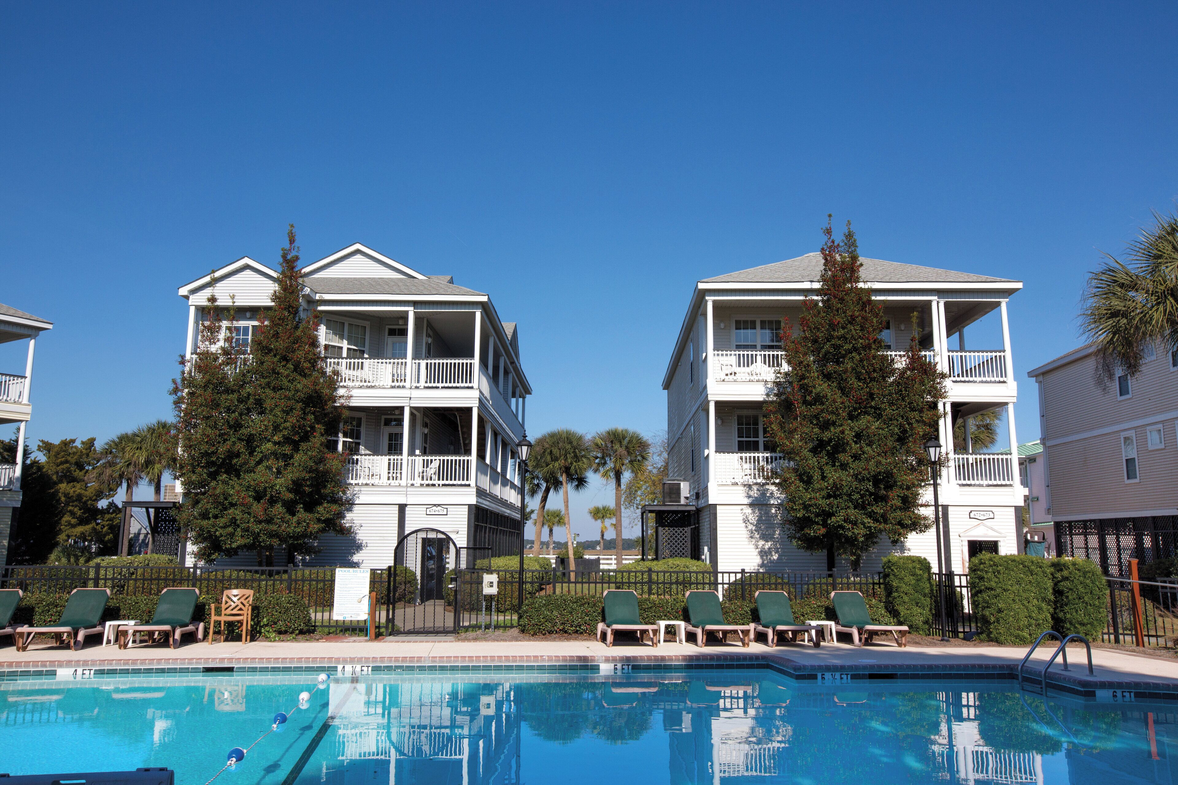 A pool area with lounge chairs and a clear blue sky.