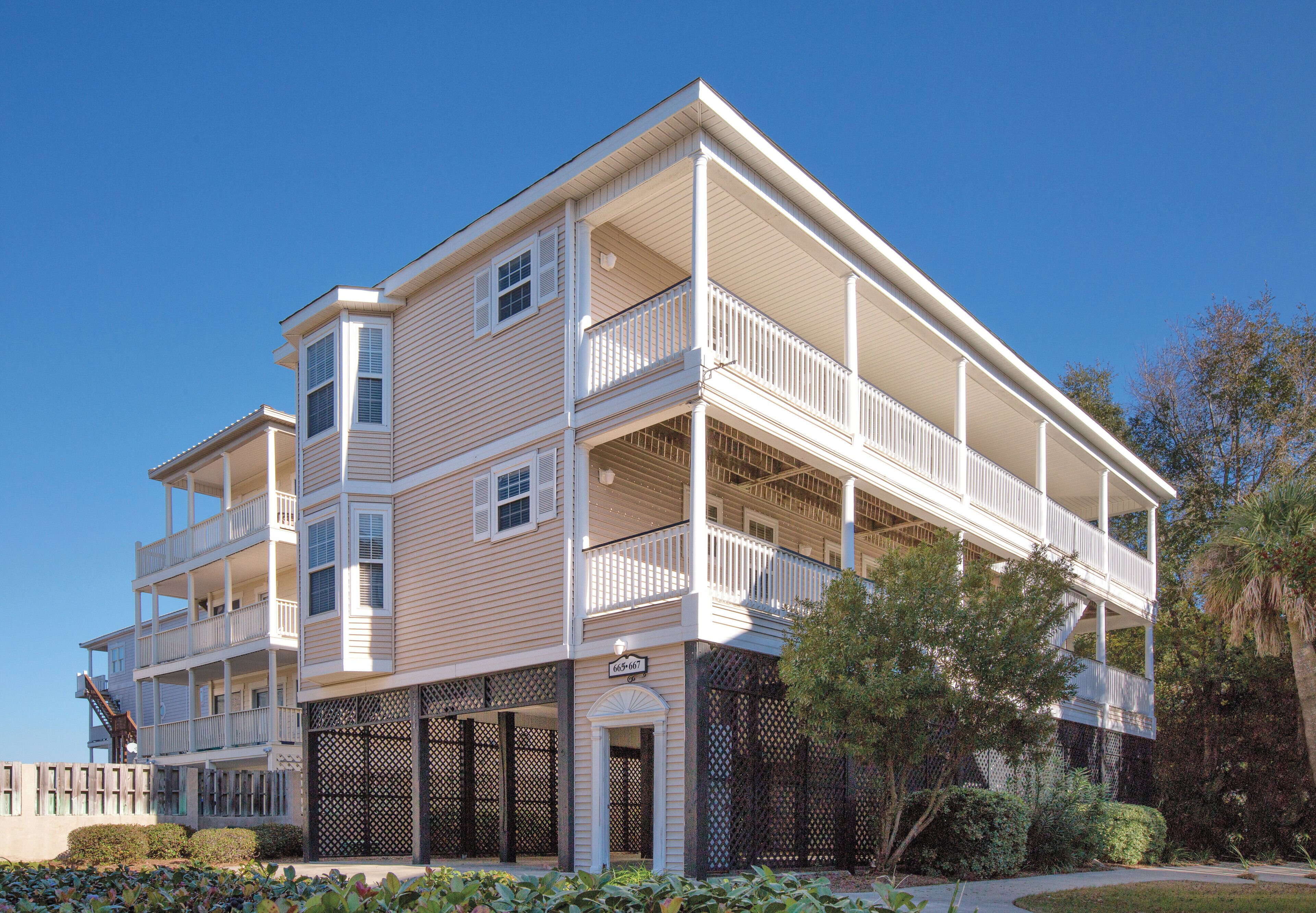 A multi-story hotel with balconies, a covered entrance, and a clear blue sky.