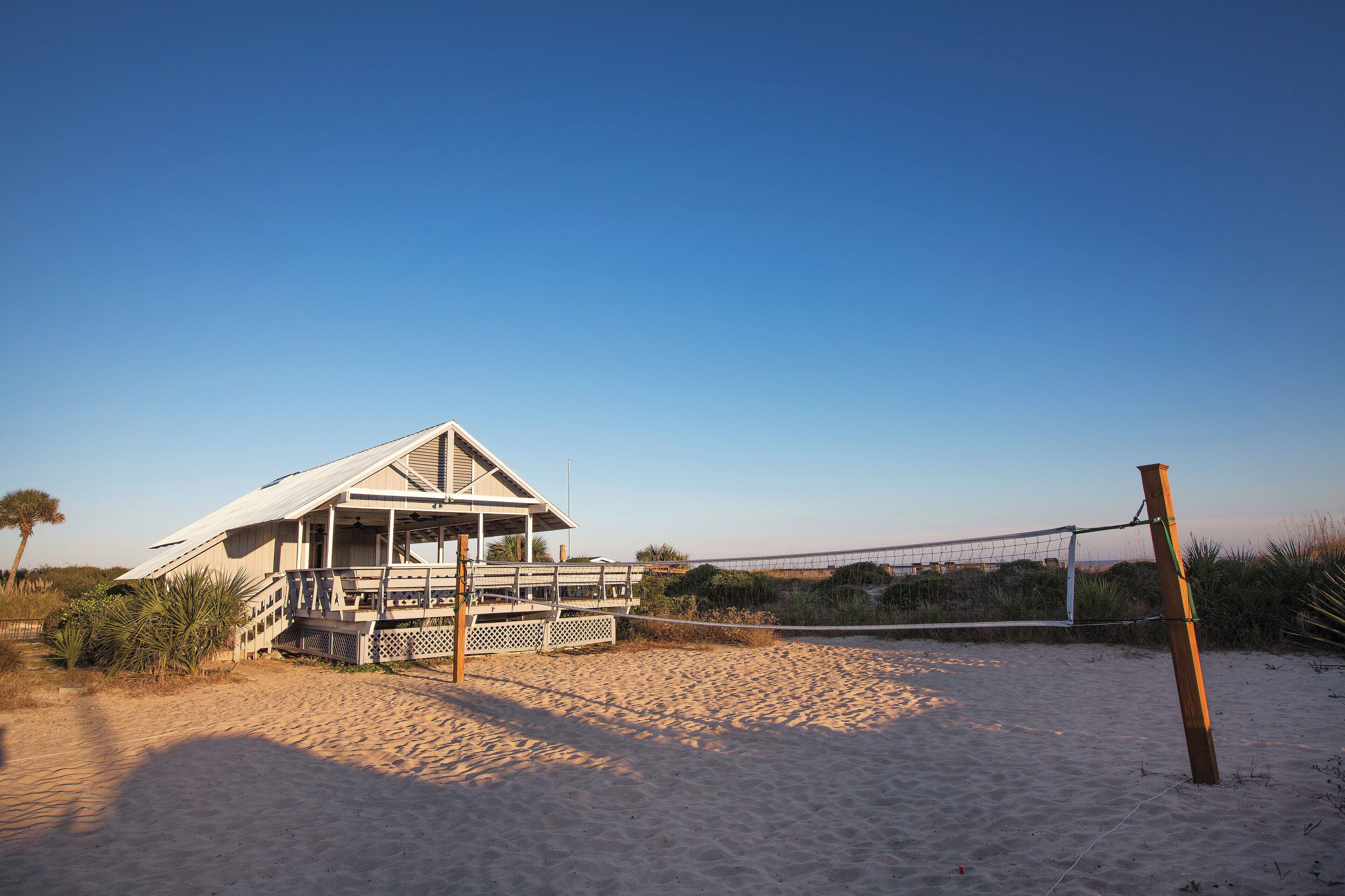 Et strandhus med veranda og volleyballnet.