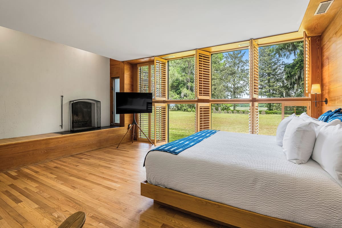 A bedroom with a large bed, a TV, and a fireplace.