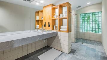 Un baño moderno con lavamanos de mármol, estantes de madera y vistas a zonas verdes a través de una ventana.