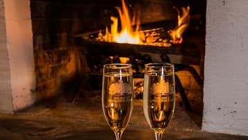 Zwei Champagnergläser mit der Aufschrift "The Inn at Middleton Place", vor einem Kamin mit sichtlichen Flammen platziert.