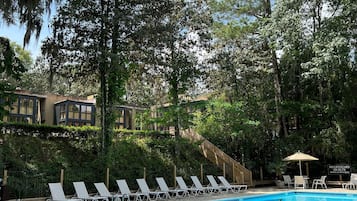 Una piscina al aire libre, sombrillas, sillones reclinables de piscina