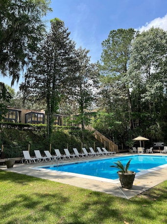 Una piscina al aire libre, sombrillas, sillones reclinables de piscina