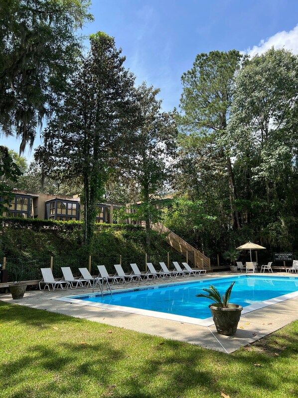 Una piscina al aire libre, sombrillas, sillones reclinables de piscina