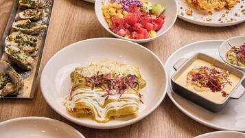 Une variété de plats sont disposés sur une table en bois, notamment des tacos, des enchiladas et des fruits de mer.