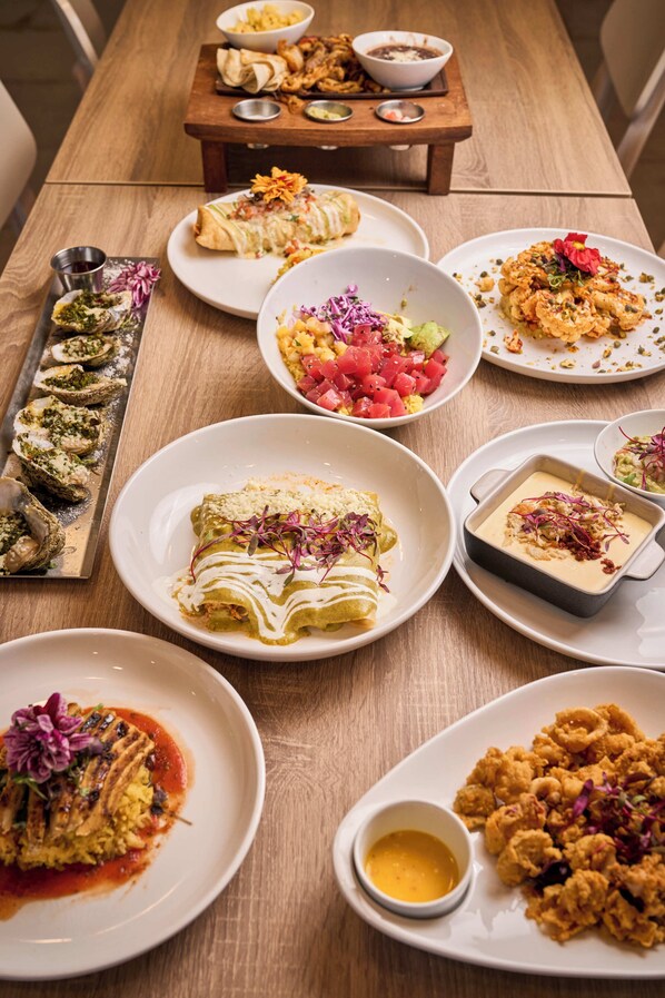 Variedad de platillos sobre una mesa de madera, incluyendo tacos, enchiladas y mariscos.