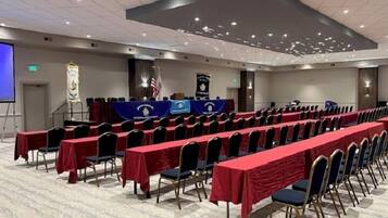 Ein Konferenzraum mit Reihen von Tischen und Stühlen, einem Rednerpult und einer Projektionsleinwand.