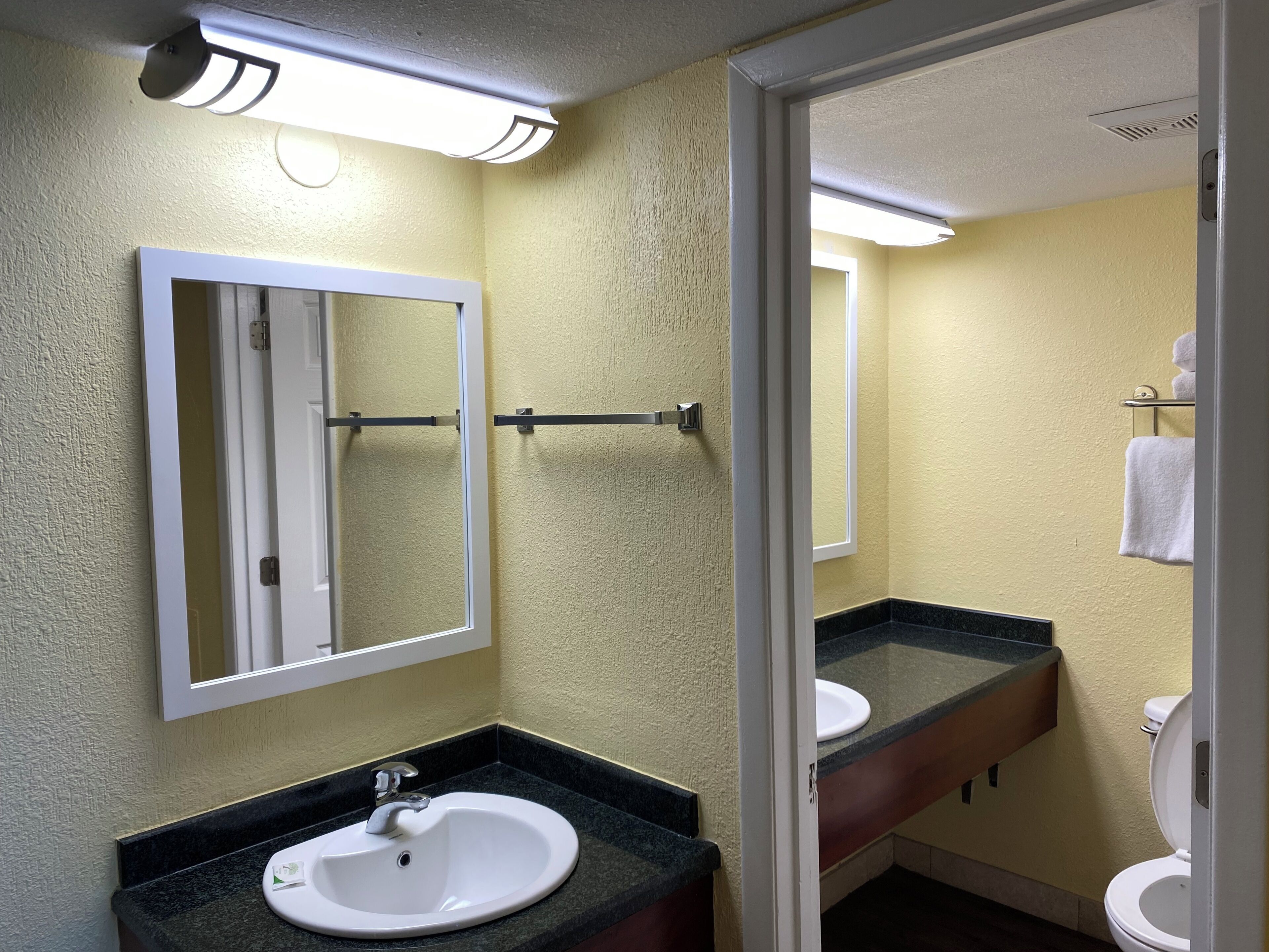 A bathroom with a white sink, a mirror, a towel rack, and a toilet.