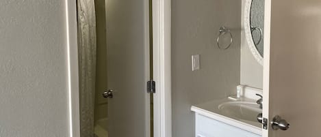 A bathroom with a toilet, sink, and mirror.