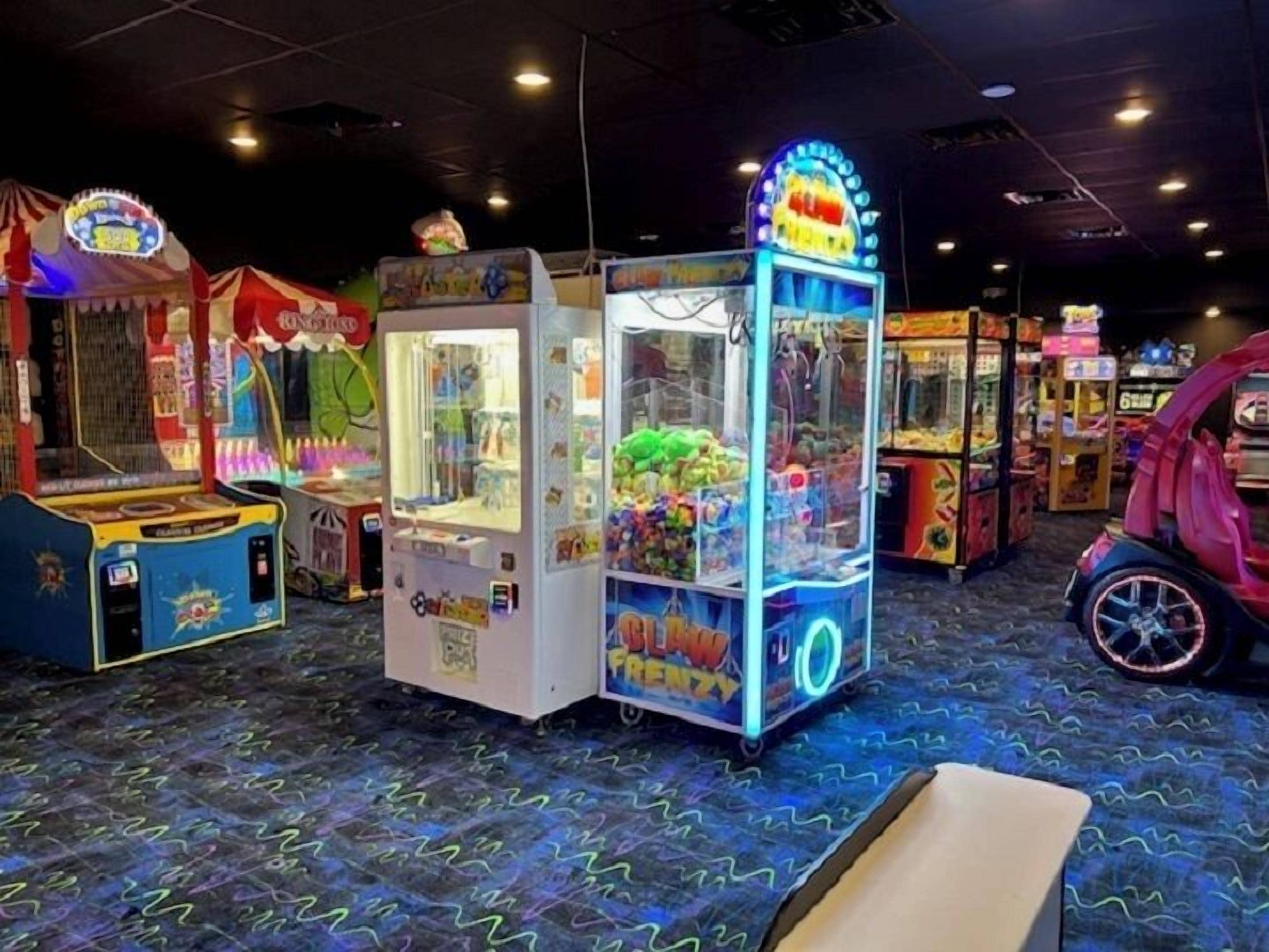 A row of arcade games in a dimly lit room with a patterned carpet.