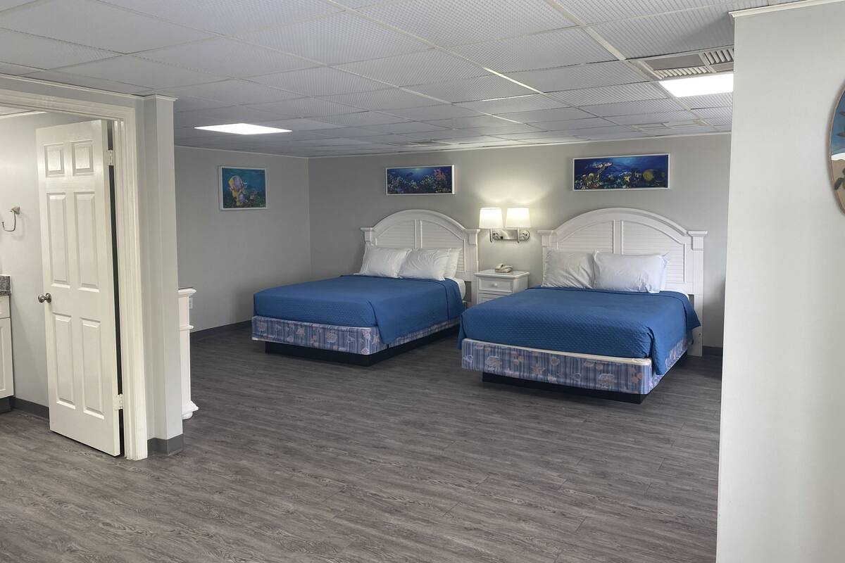 Ein Hotelzimmer mit zwei Betten, einer weißen Tür und Bildern an den Wänden.