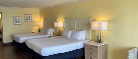 A hotel room with two beds, bedside tables with lamps, a wooden floor, and a chair.