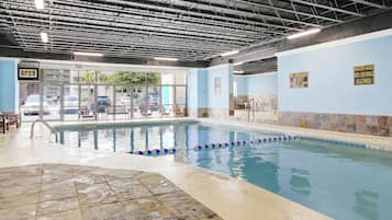 An indoor swimming pool with clear water, marked lanes, and safety signs.