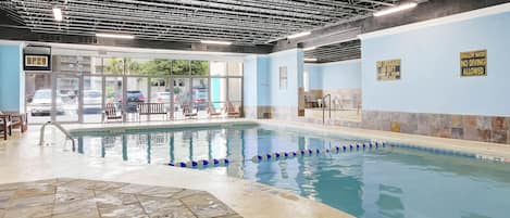 An indoor swimming pool with clear water, marked lanes, and safety signs.