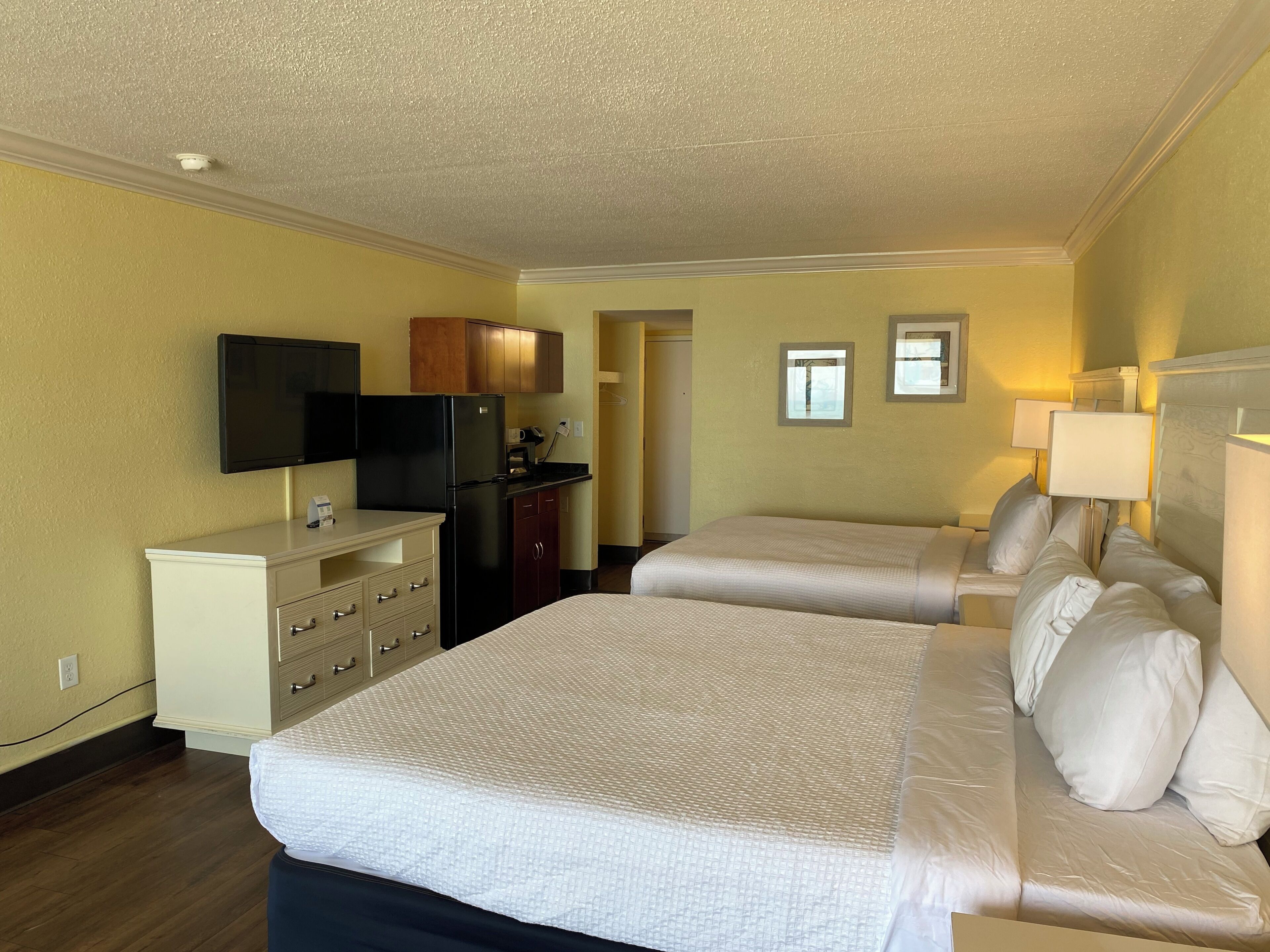Quarto de hotel com duas camas, televisão, escrivaninha, frigorífico e micro-ondas.