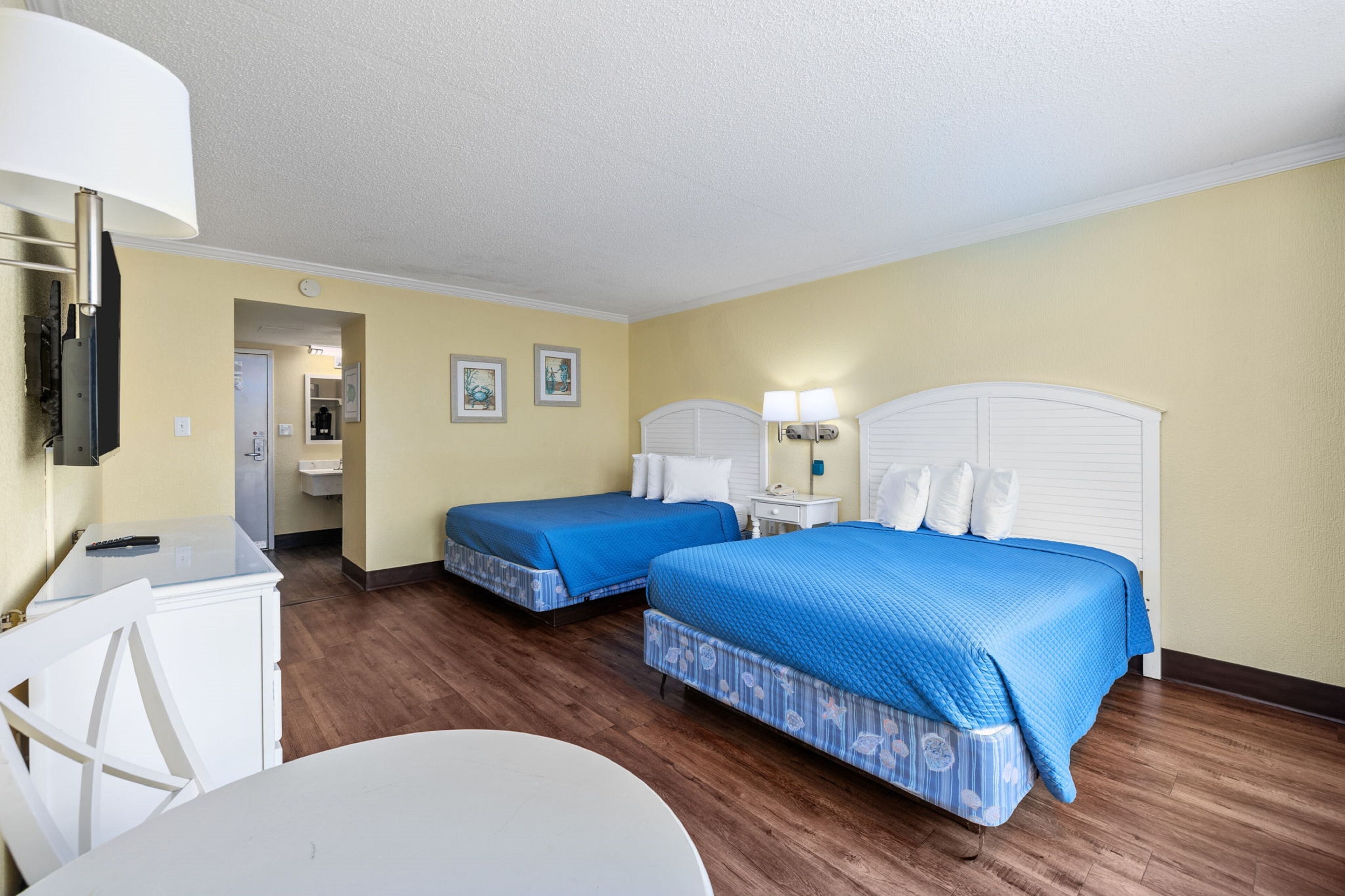 Une chambre d’hôtel avec deux lits, un bureau, une chaise et une petite table.