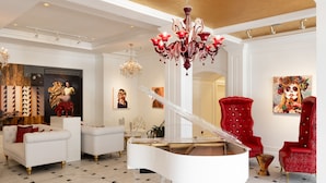Una sala imponente con un piano de cola, sillas rojas y un candelabro.