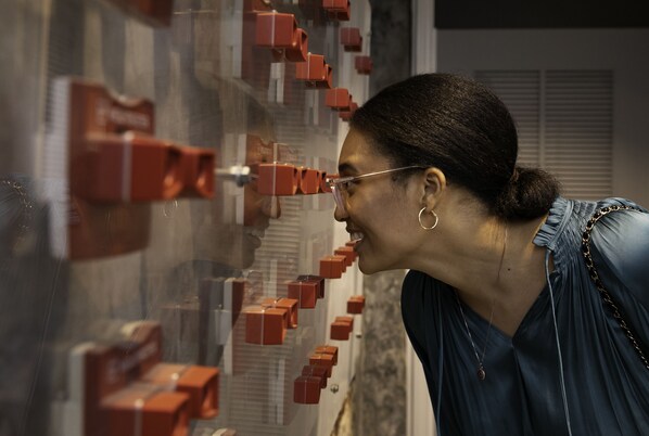 A person standing in front of a wall with multiple red objects. - The Vendue (Charleston)
