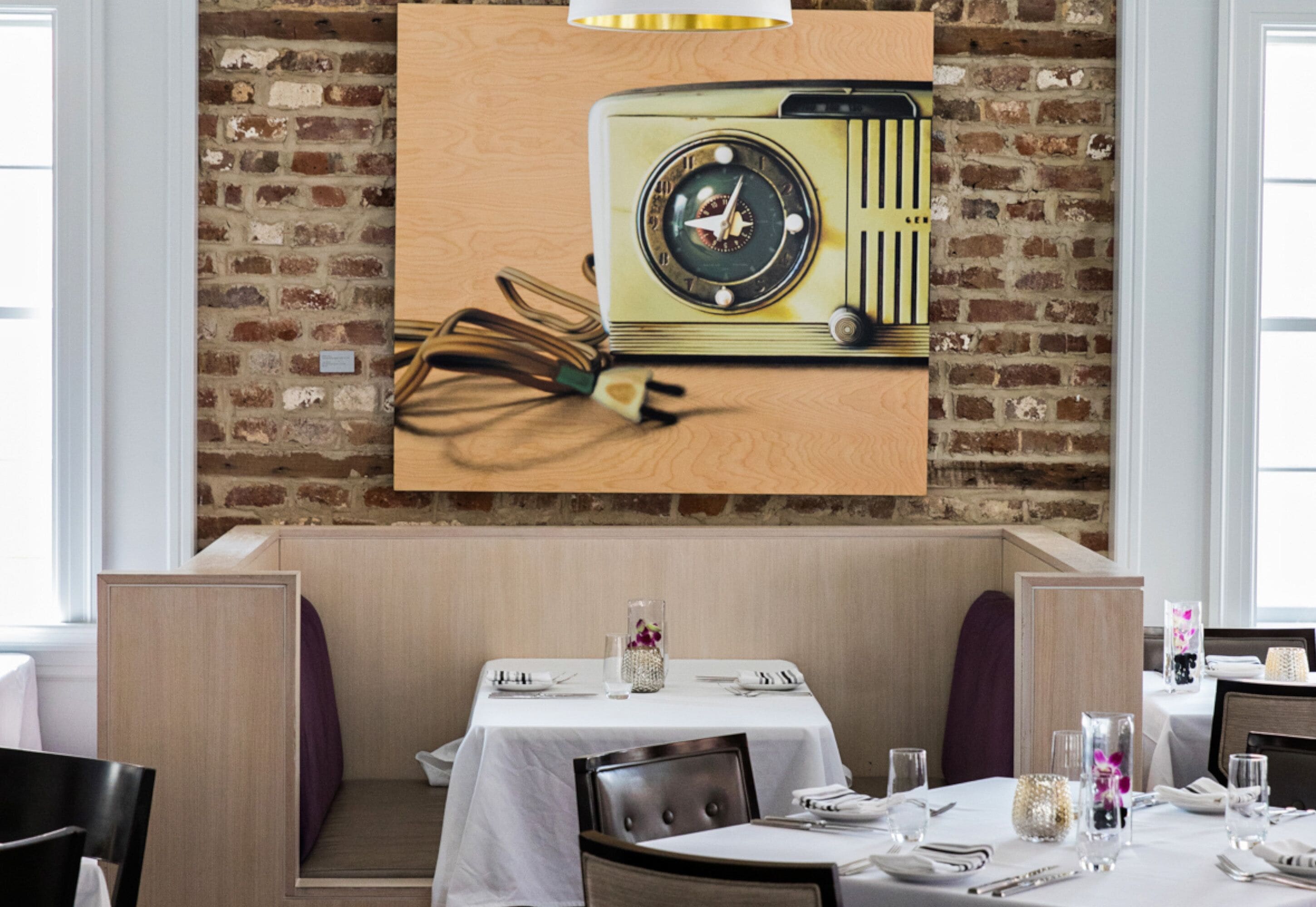 Restaurante com parede de tijolos, rádio antigo e mesa posta para refeição.