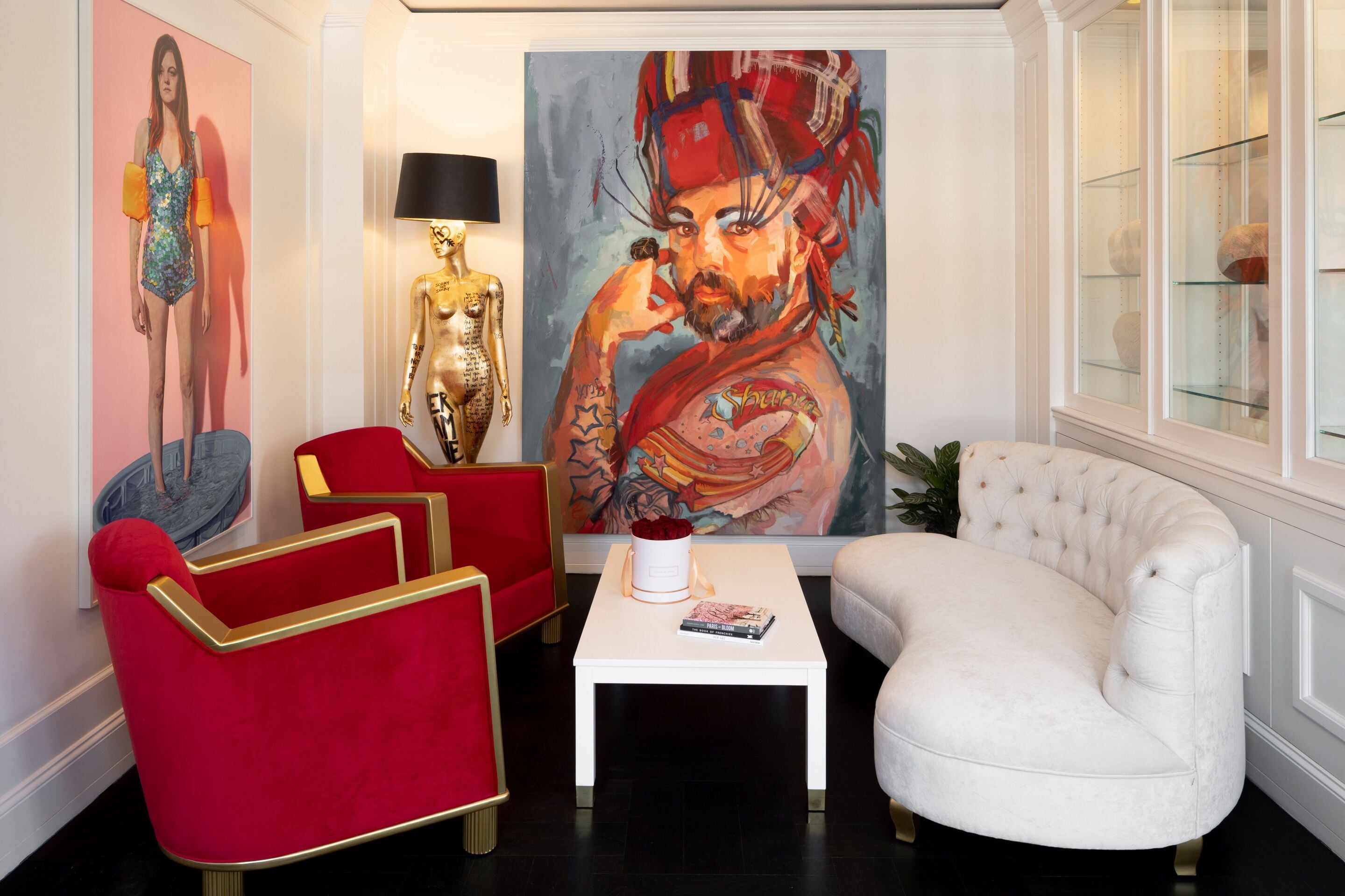 Una sala de estar moderna con un sillón rojo, un sofá blanco y un cuadro grande en la pared.