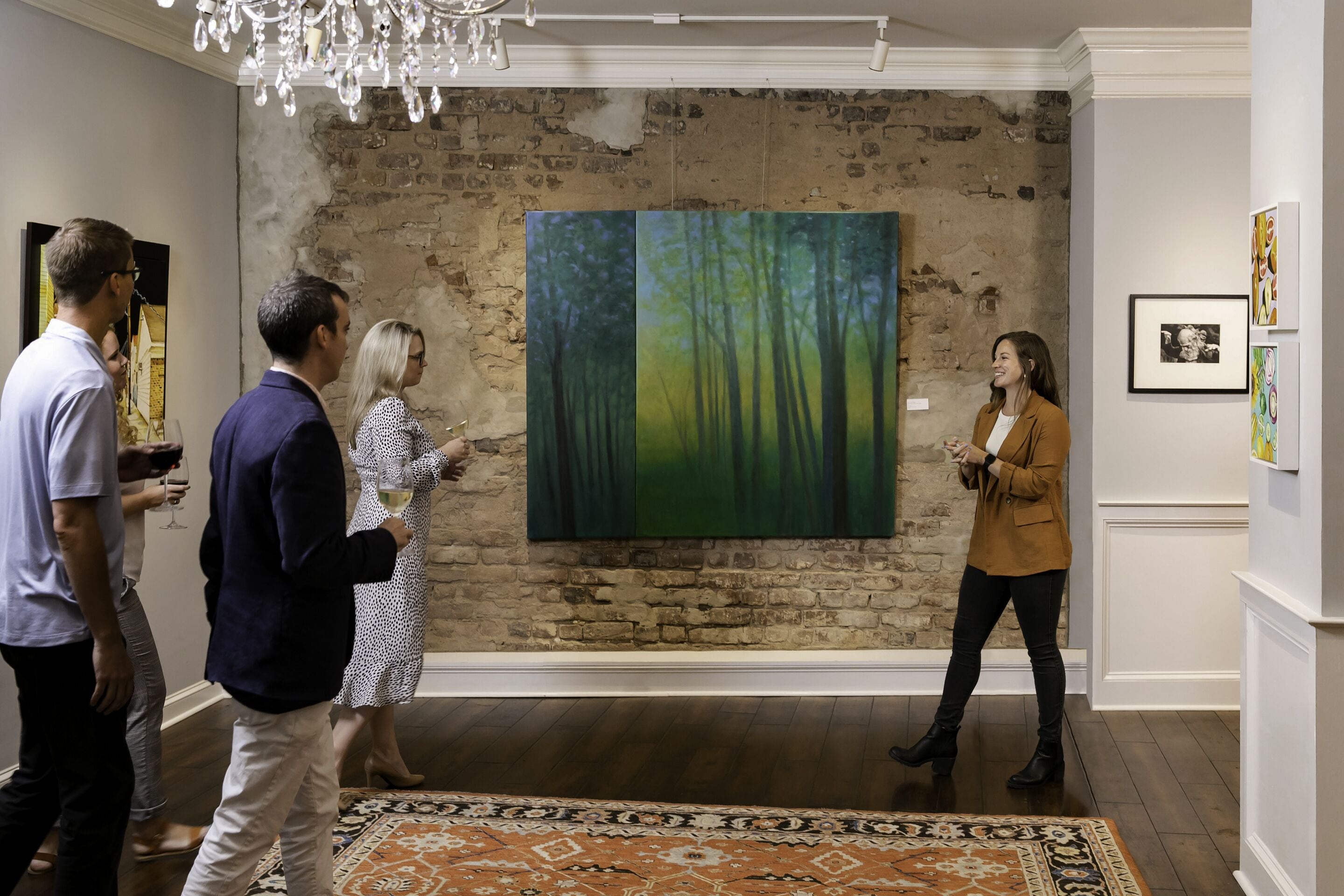 Una galería de arte con una pared de ladrillo rústica y un cuadro de gran formato con temática forestal.