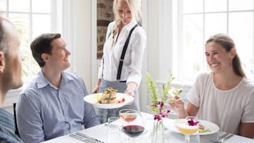 A dining table with plates of food, wine glasses, and a vase with flowers.